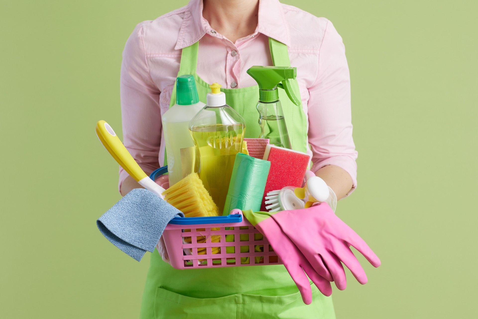 Modern housewife in green apron and rubber gloves on green
