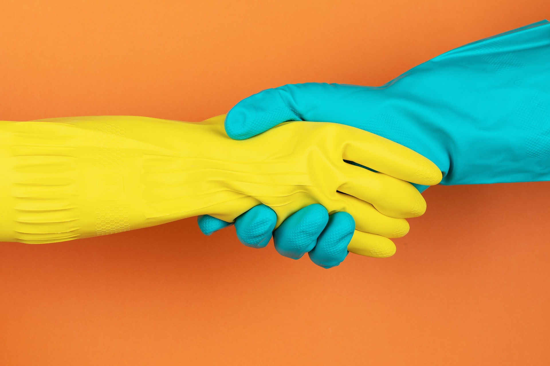 Handshaking in Rubber Gloves on Orange Background